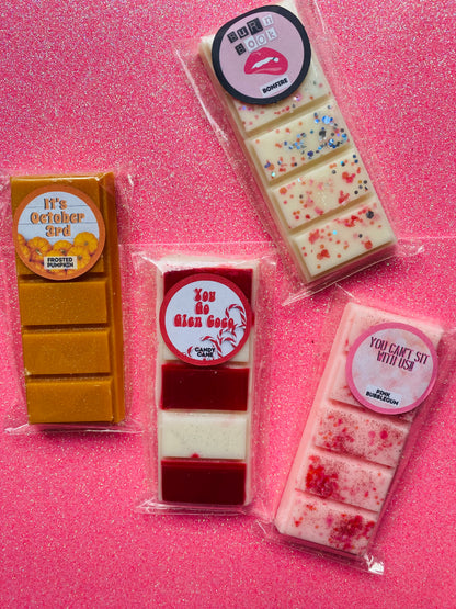 Four packaged wax melts inspired by the Mean Girls movie, each with different colors and labels corresponding to different quotes from the film.